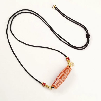 Red flesh agate nine eye dzi bead pendant necklace with gold spacers and black cord.