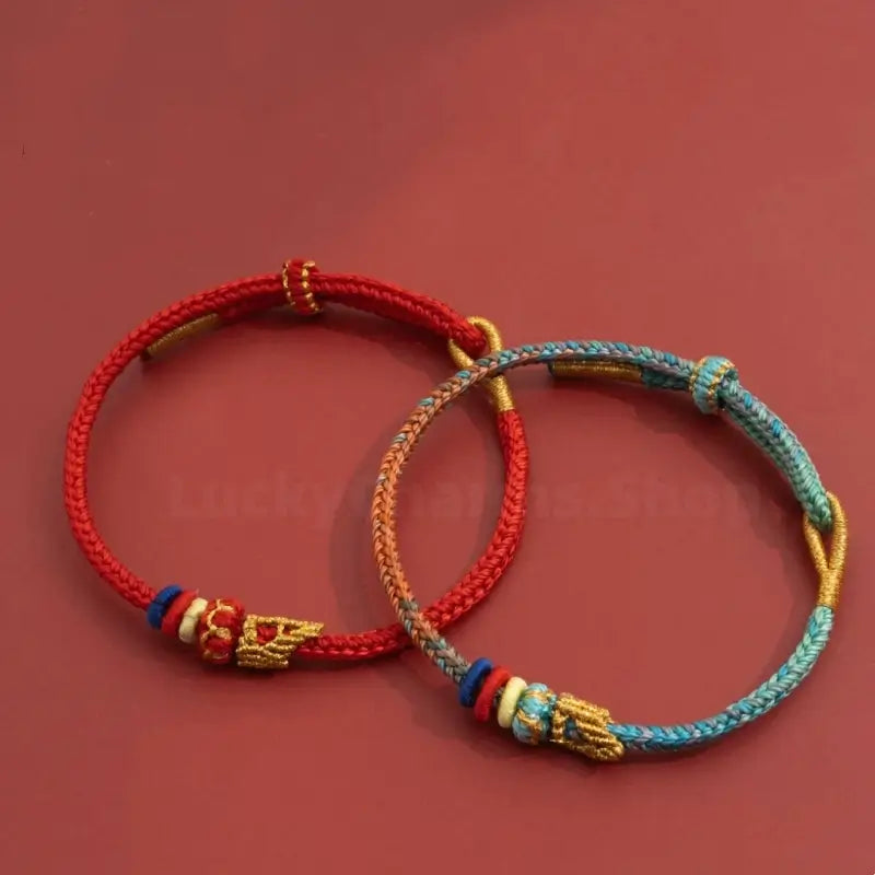 Red and two-tone blue hand-woven Buddhist knot lucky cord bracelets on dark red background.