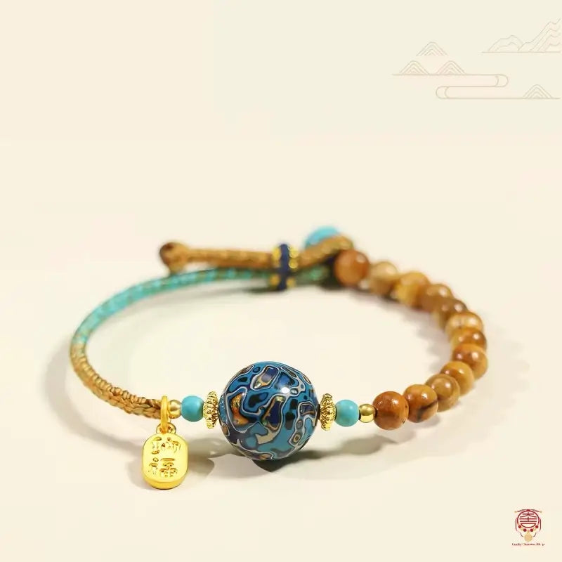 Handcrafted lacquer bead bracelet with golden phoebe wood beads, turquoise, and gold Fu charm on white background.