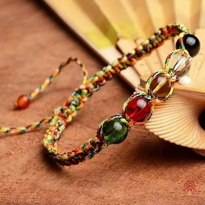 Close-up of a Manjushri five elements protection bracelet with colorful braided rope and clear crystal beads.