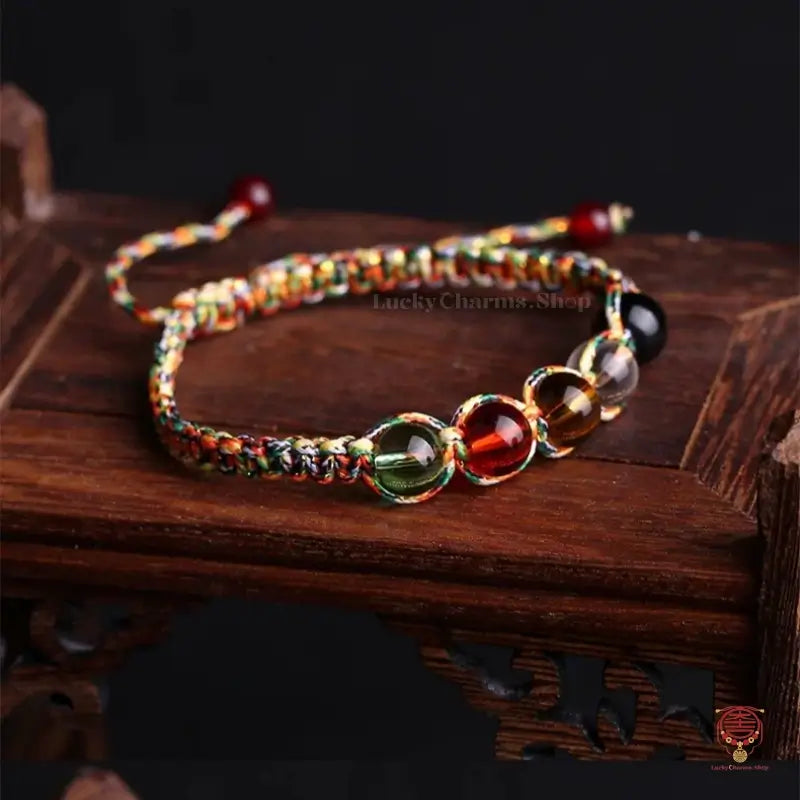 Natural gemstone five elements protection knot bracelet displayed on a vintage dark brown wooden stand.